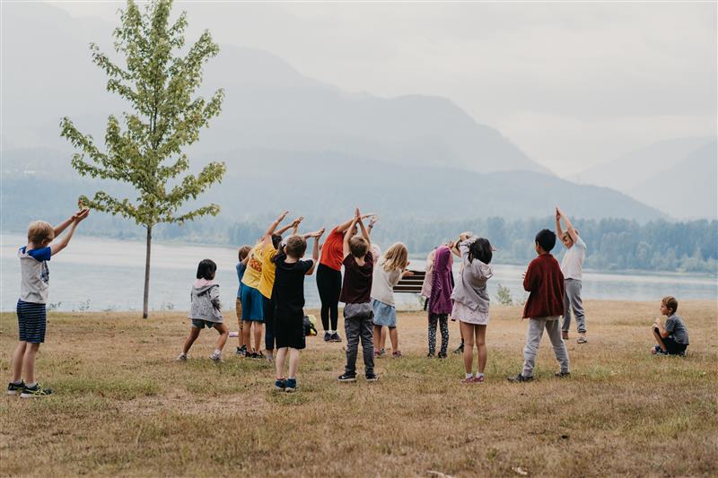 Children Doing Stretches by the River as Part of a Community Group